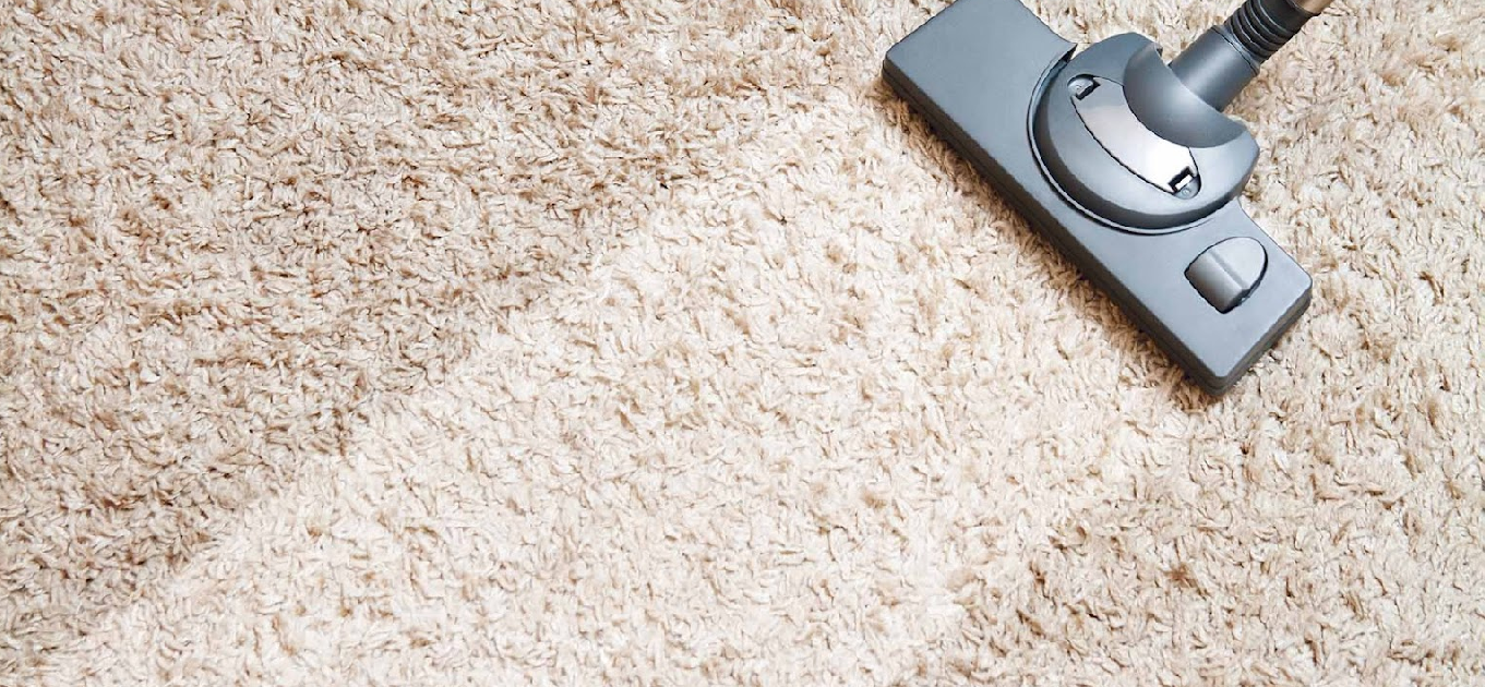 A vacuum cleaner is being used to clean a carpet.