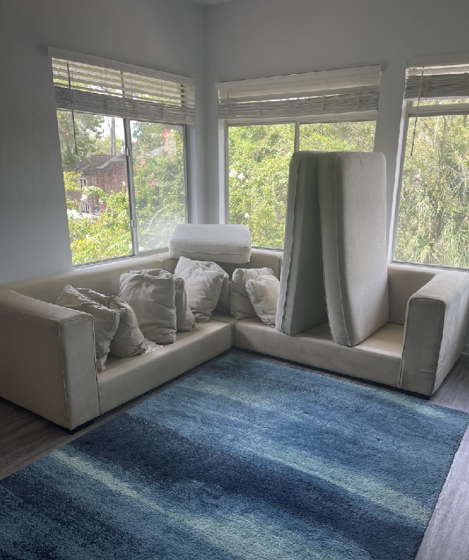 A living room with a white couch and a blue rug.