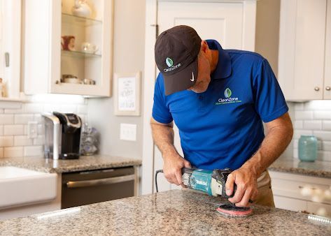 A man is polishing a granite counter top in a kitchen.