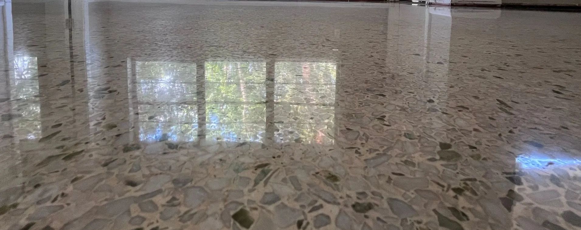 A close up of a shiny concrete floor with a window in the background.