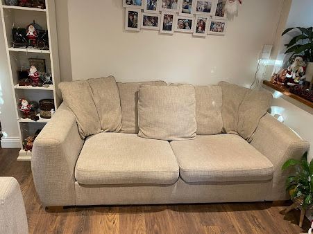 A beige couch is sitting in a living room next to a bookshelf.
