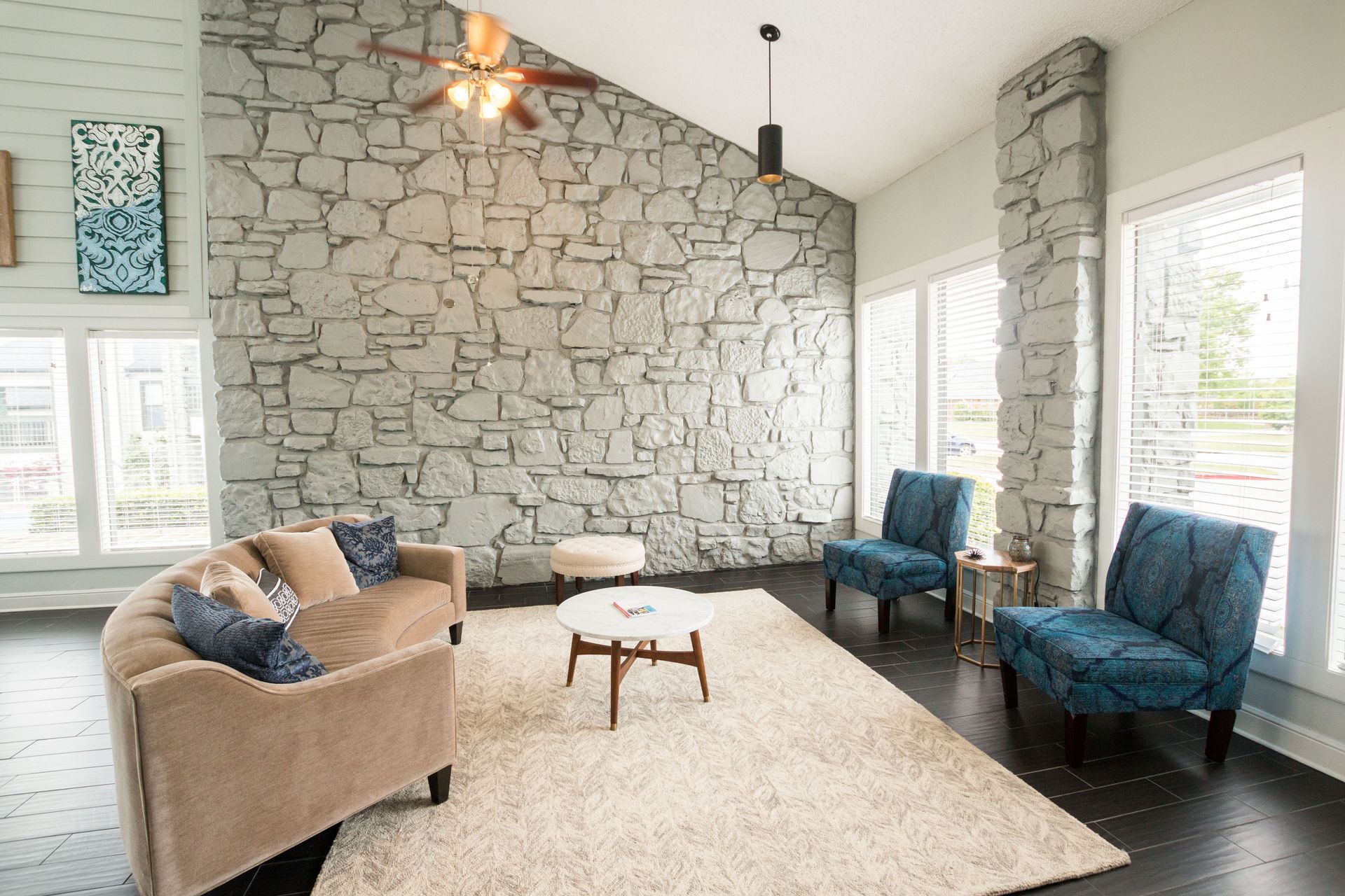 A living room with a couch , chairs , and a ceiling fan.