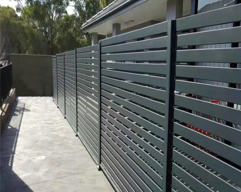 A gray fence is surrounding a patio in front of a house.