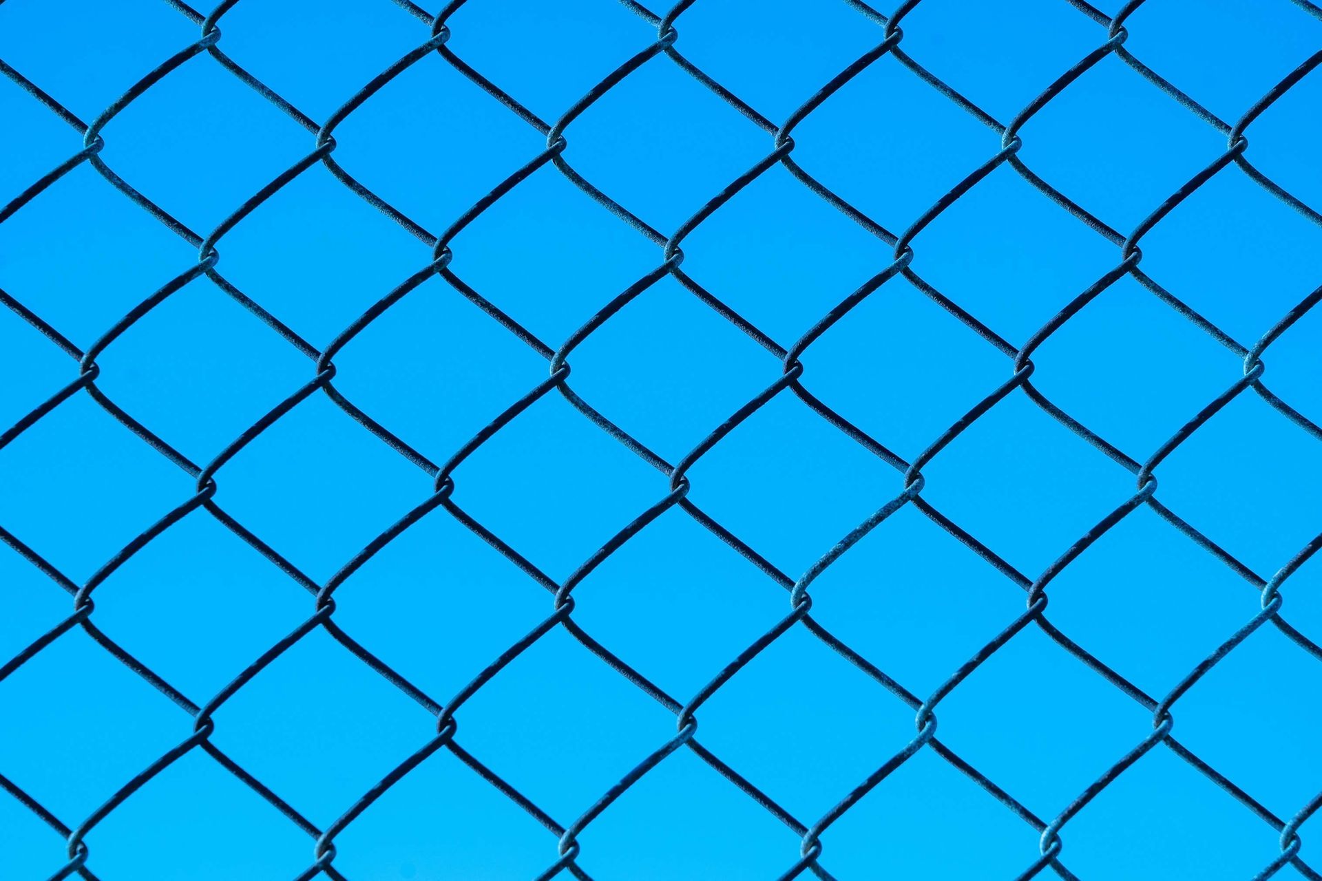 A chain link fence against a blue sky