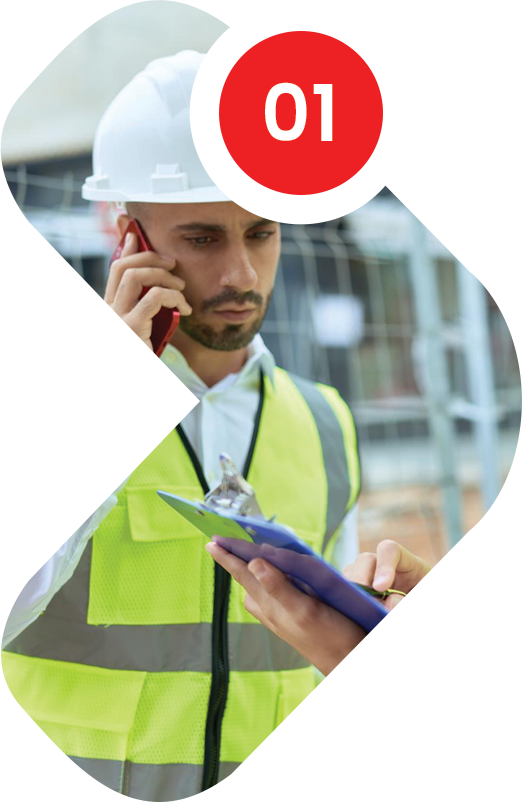 Construction worker in vest and helmet on phone, reviewing clipboard.