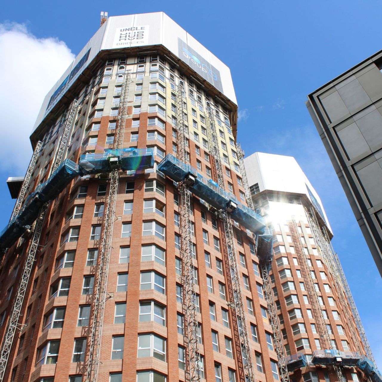 Two tall brick apartment buildings under construction against a bright blue sky.