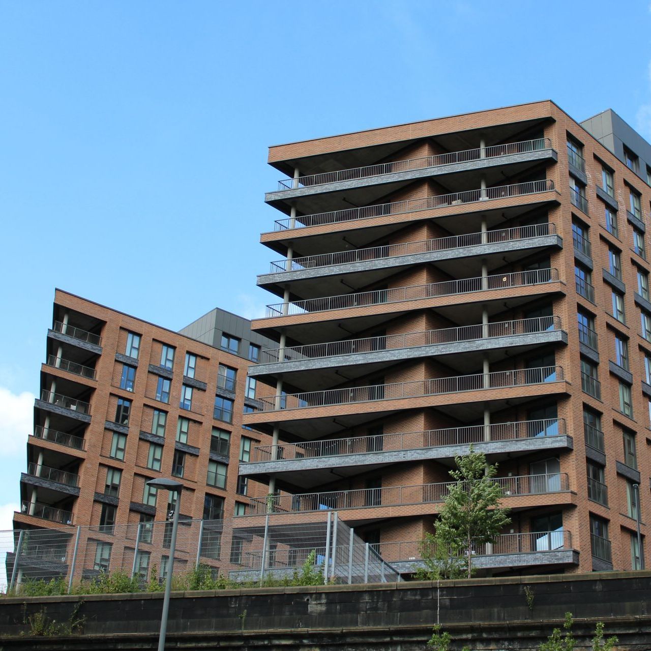 Brick apartment buildings with balconies against a blue sky.