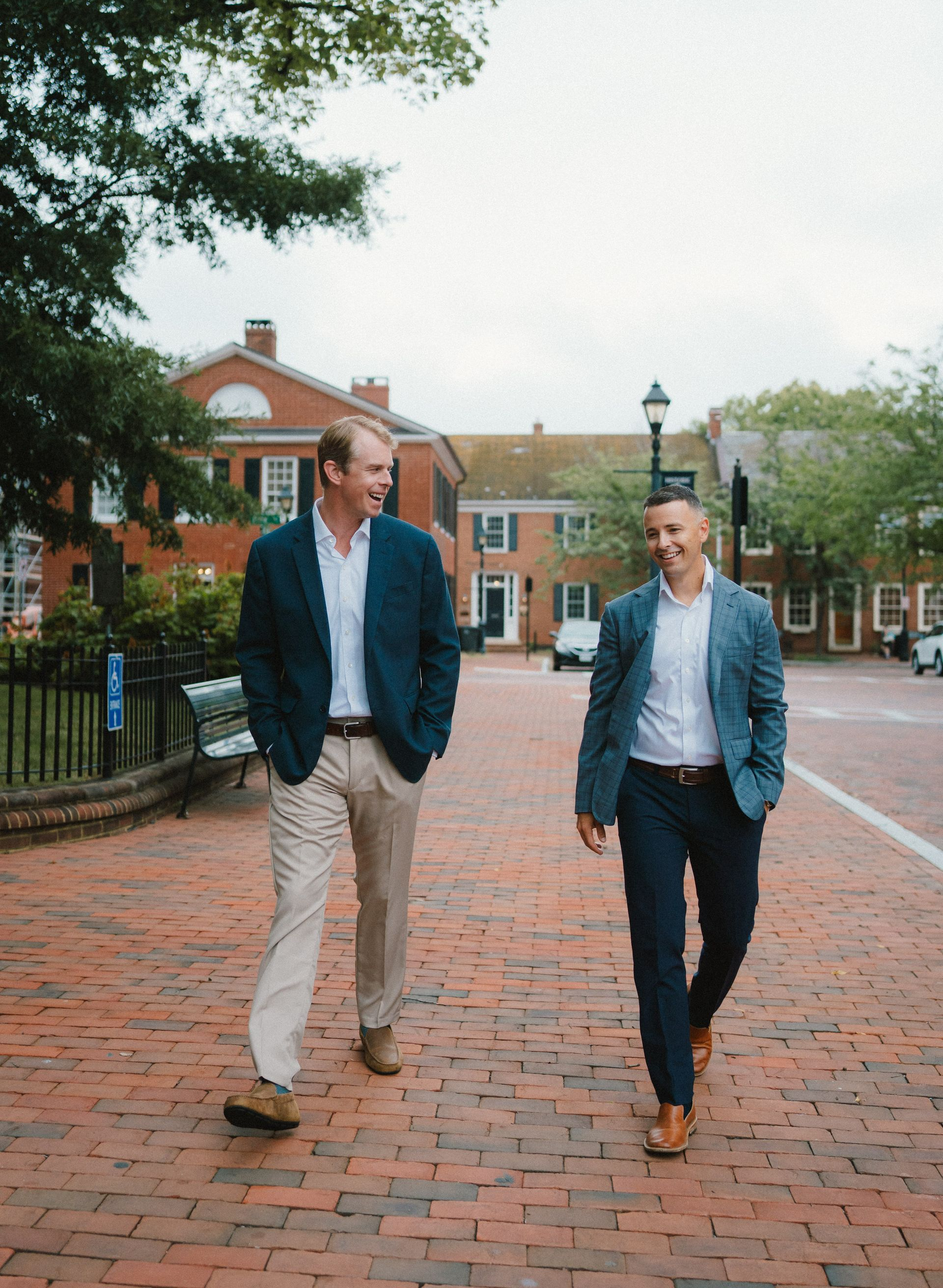 Silhouetted figures watching sunset over a calm body of water; orange and gray sky.
