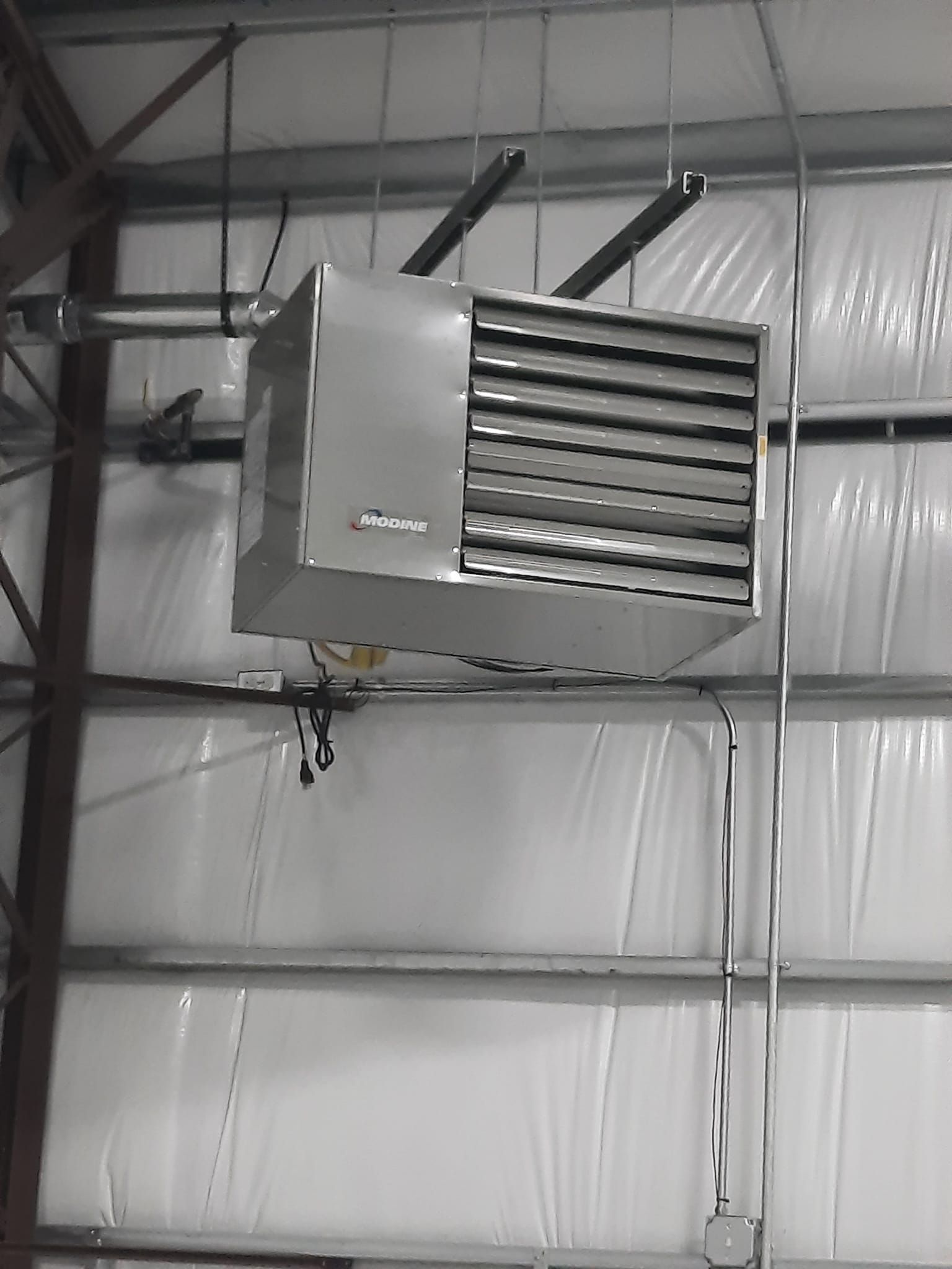 A large heater is hanging from the ceiling of a building