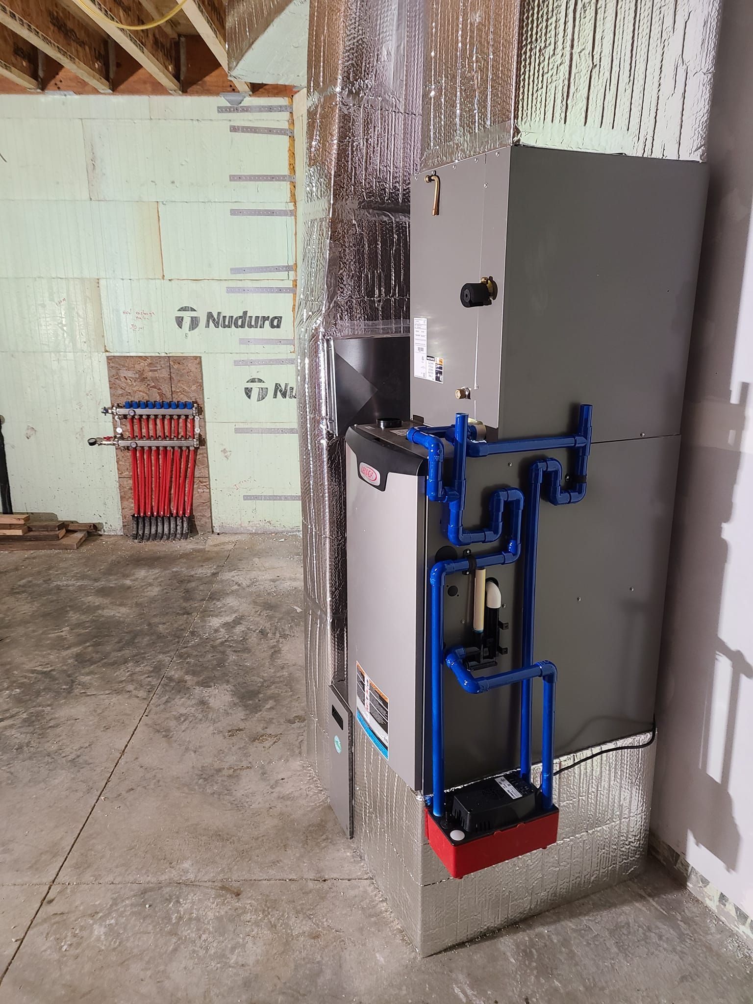 A boiler is sitting in a basement next to a wall.