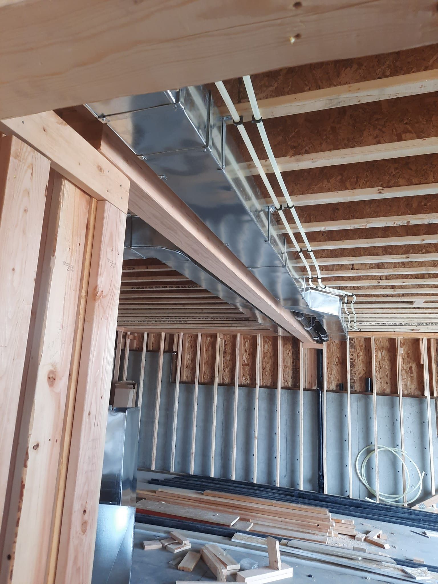 A building under construction with wooden beams and a metal pipe coming out of the ceiling.