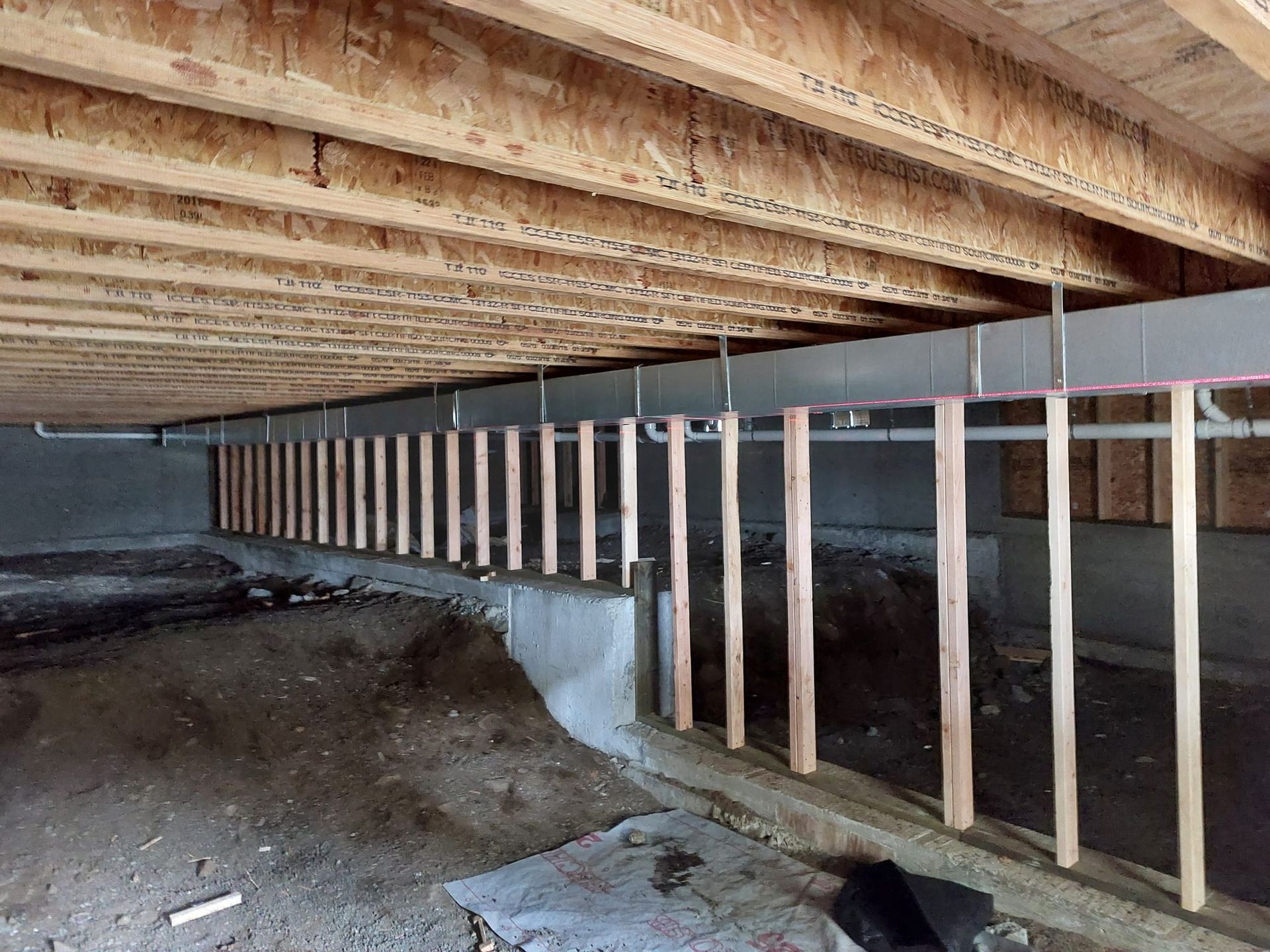 A basement under construction with wooden beams and pipes.