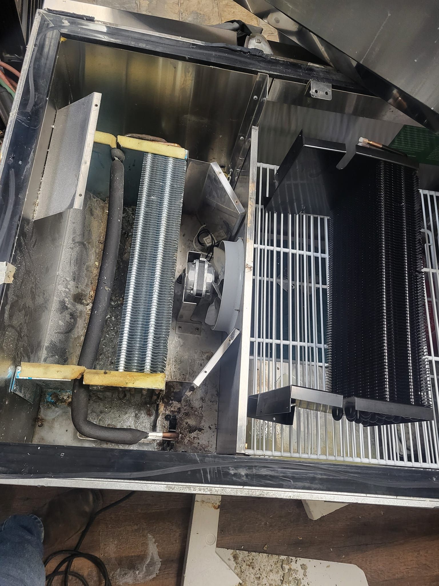 A dirty air conditioner is sitting on the floor in a room.