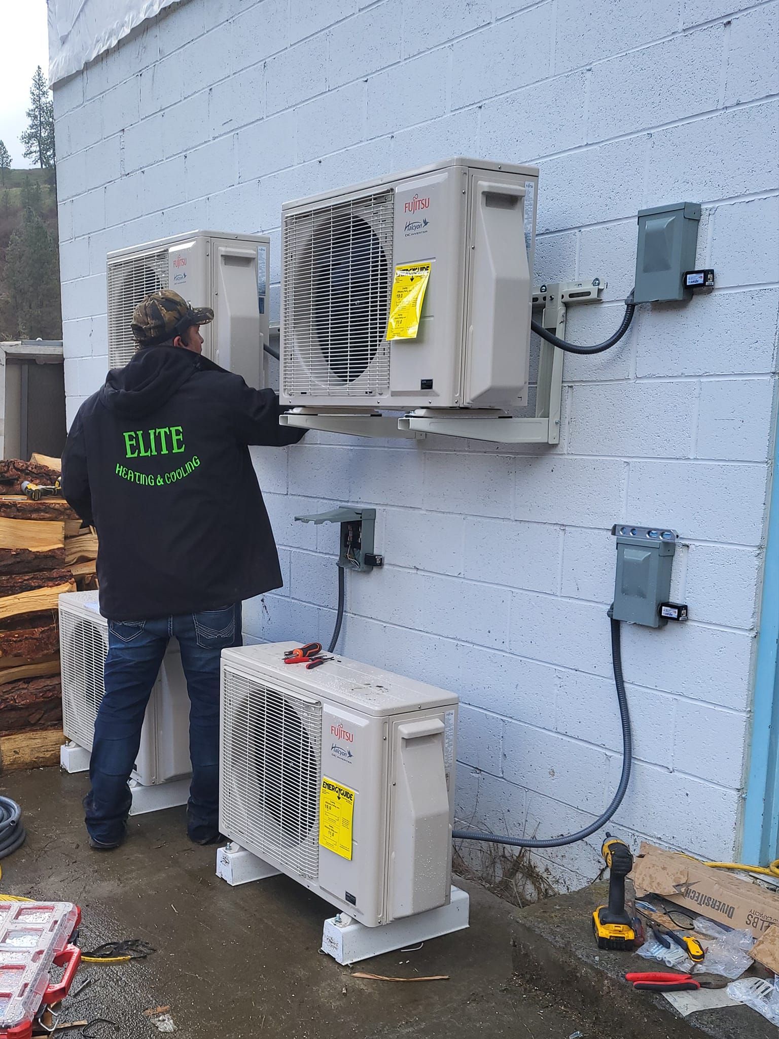 A man is installing air conditioners on the side of a building.