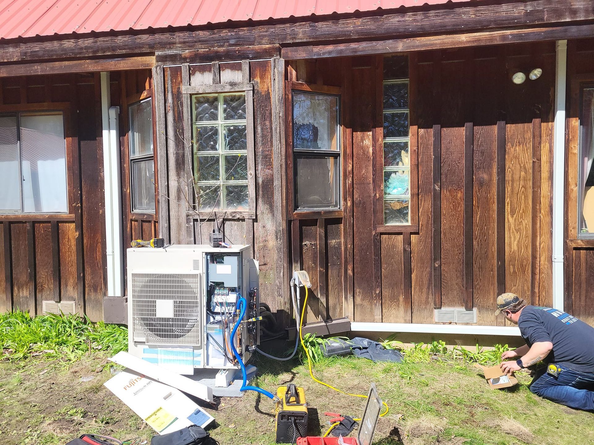 A man is kneeling in front of a wooden house.