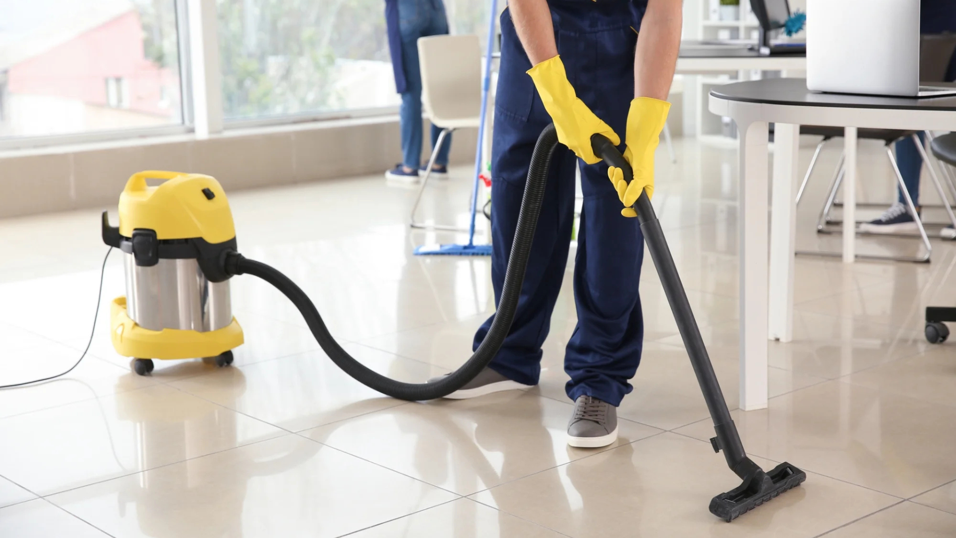 Person kneeling, measuring a wooden plank during floor installation, with tools nearby.