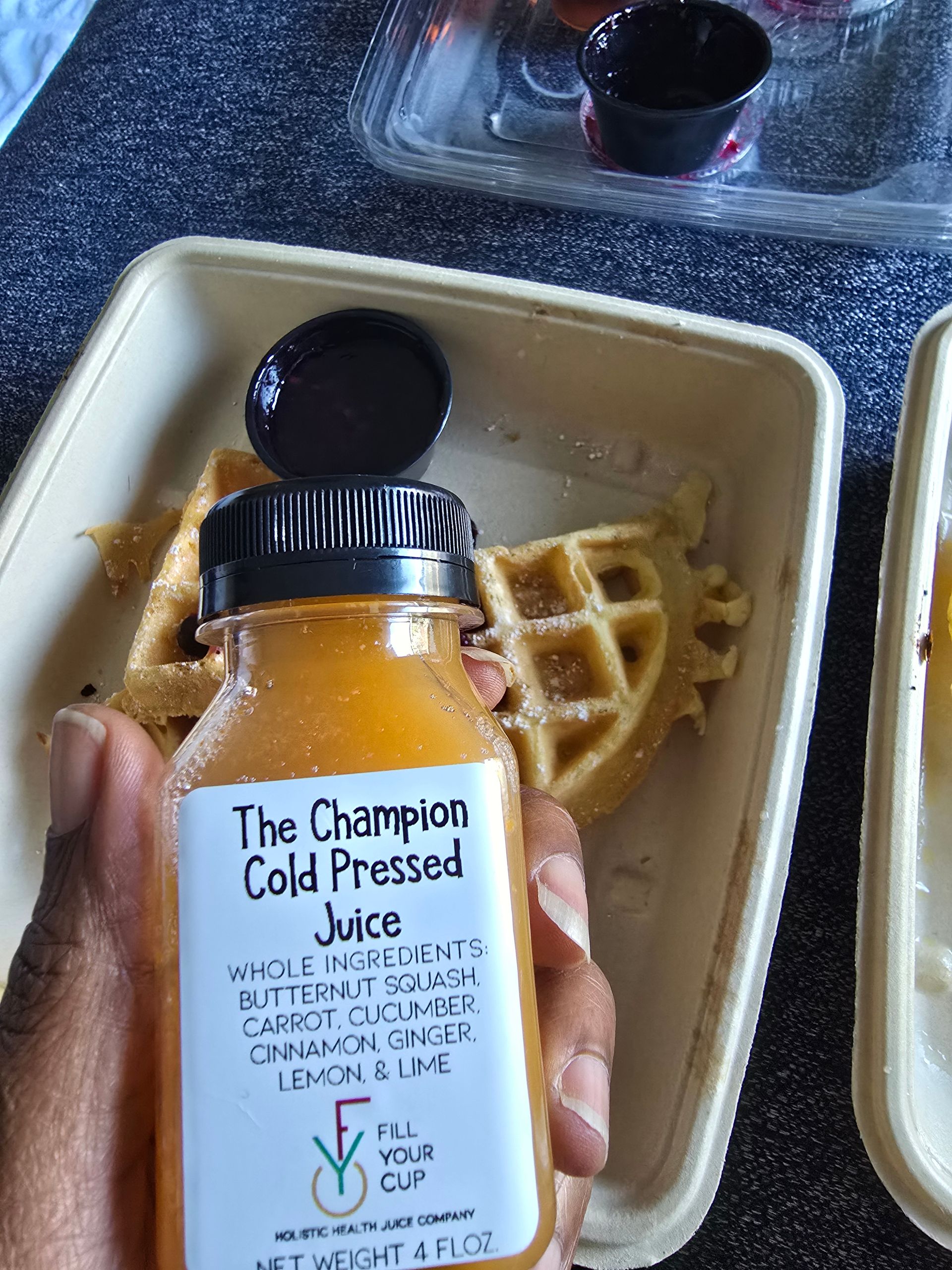 Person holding a juice bottle with waffles in a container.