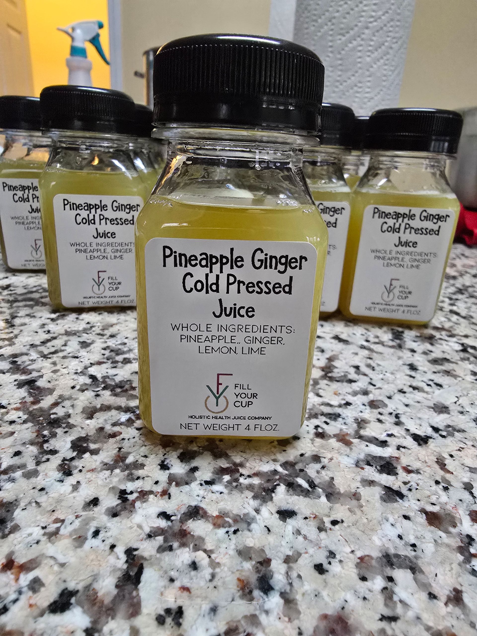 Bottles of Pineapple Ginger cold-pressed juice on a countertop.