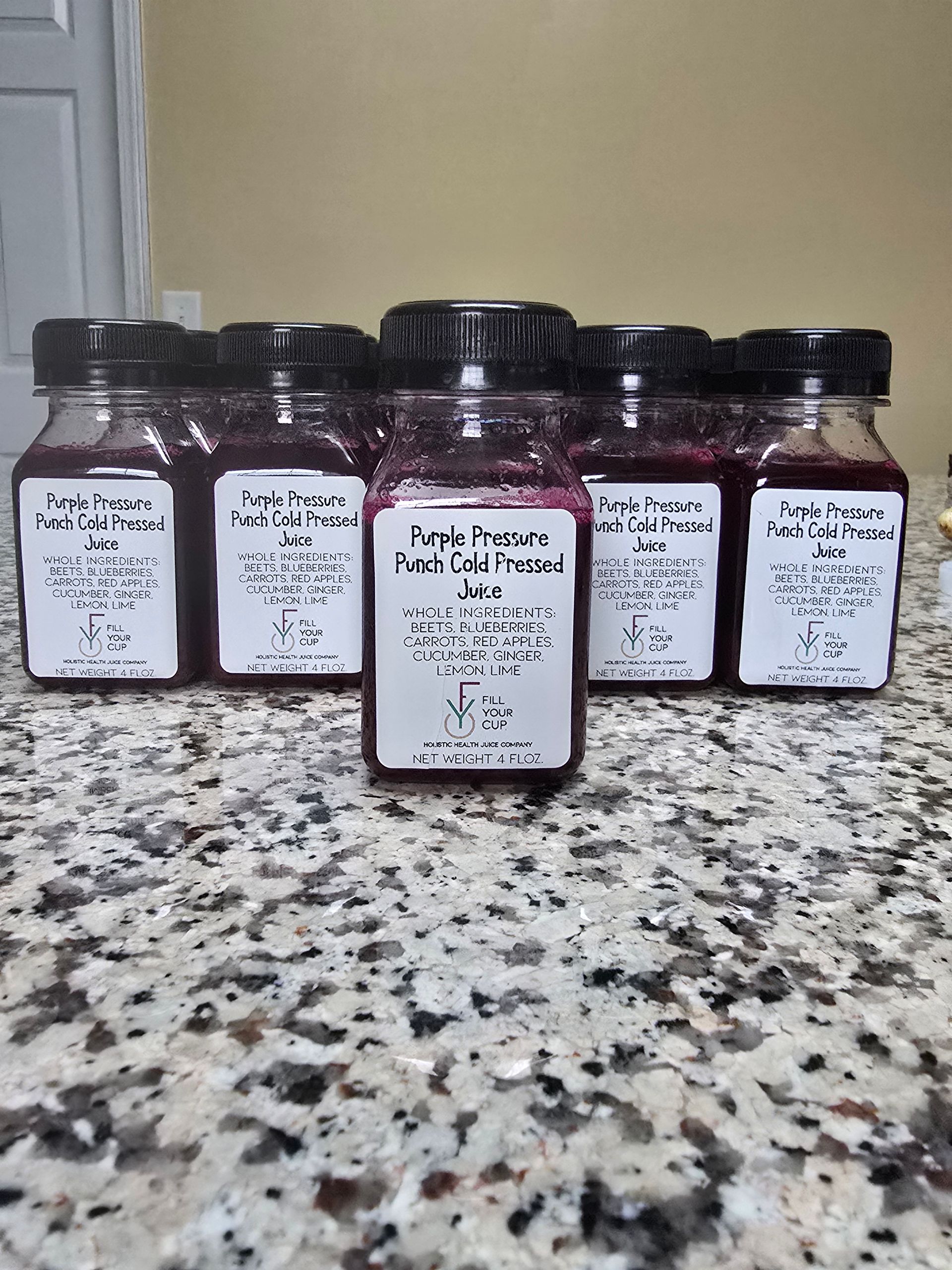 Six jars of purple liquid with labels on a speckled countertop.