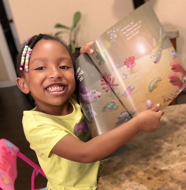 a little girl holding a book from Reach Out & Read