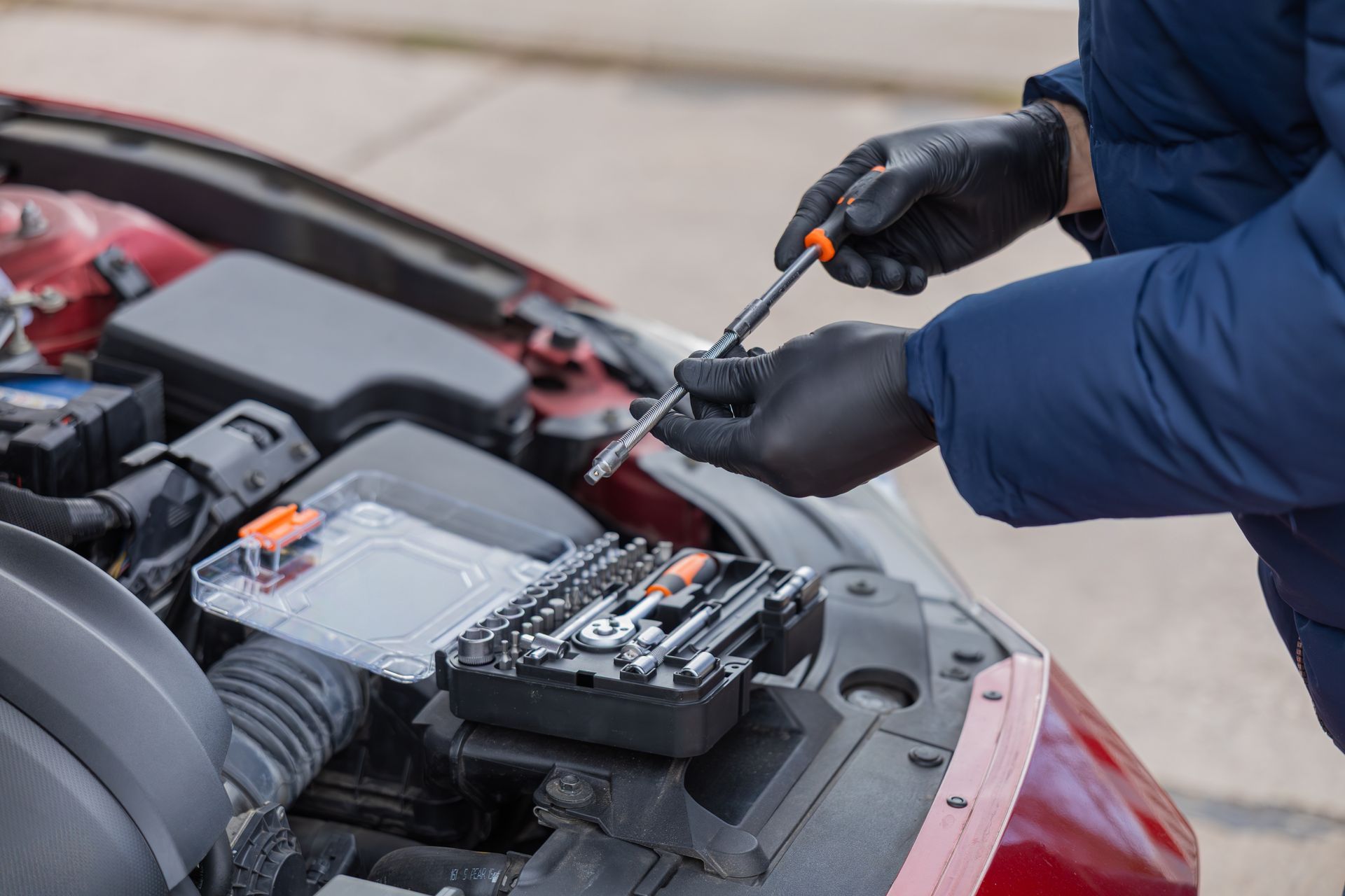 Mechanic jump-starting a car battery with jumper cables under the hood