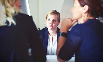 A group of women are sitting at a table having a conversation.