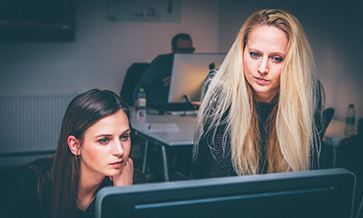 Two women are looking at a computer screen together.