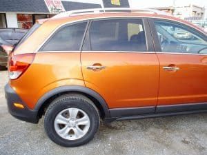 An orange car is parked in front of a building.