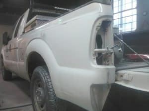 A white truck is being painted in a garage.