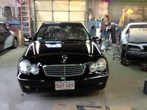 A black mercedes benz is parked in a garage.