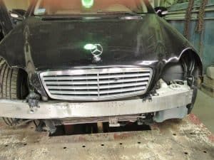 A black mercedes benz is sitting on a table in a garage.