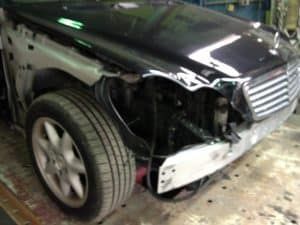A black mercedes benz is being repaired in a garage.
