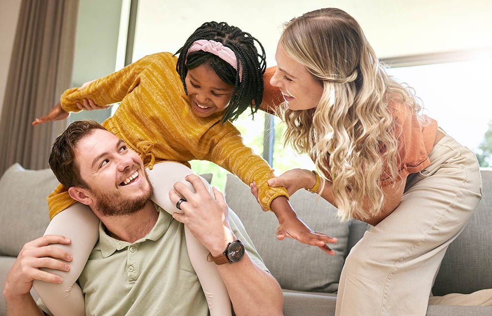 A man is carrying a little girl on his shoulders.