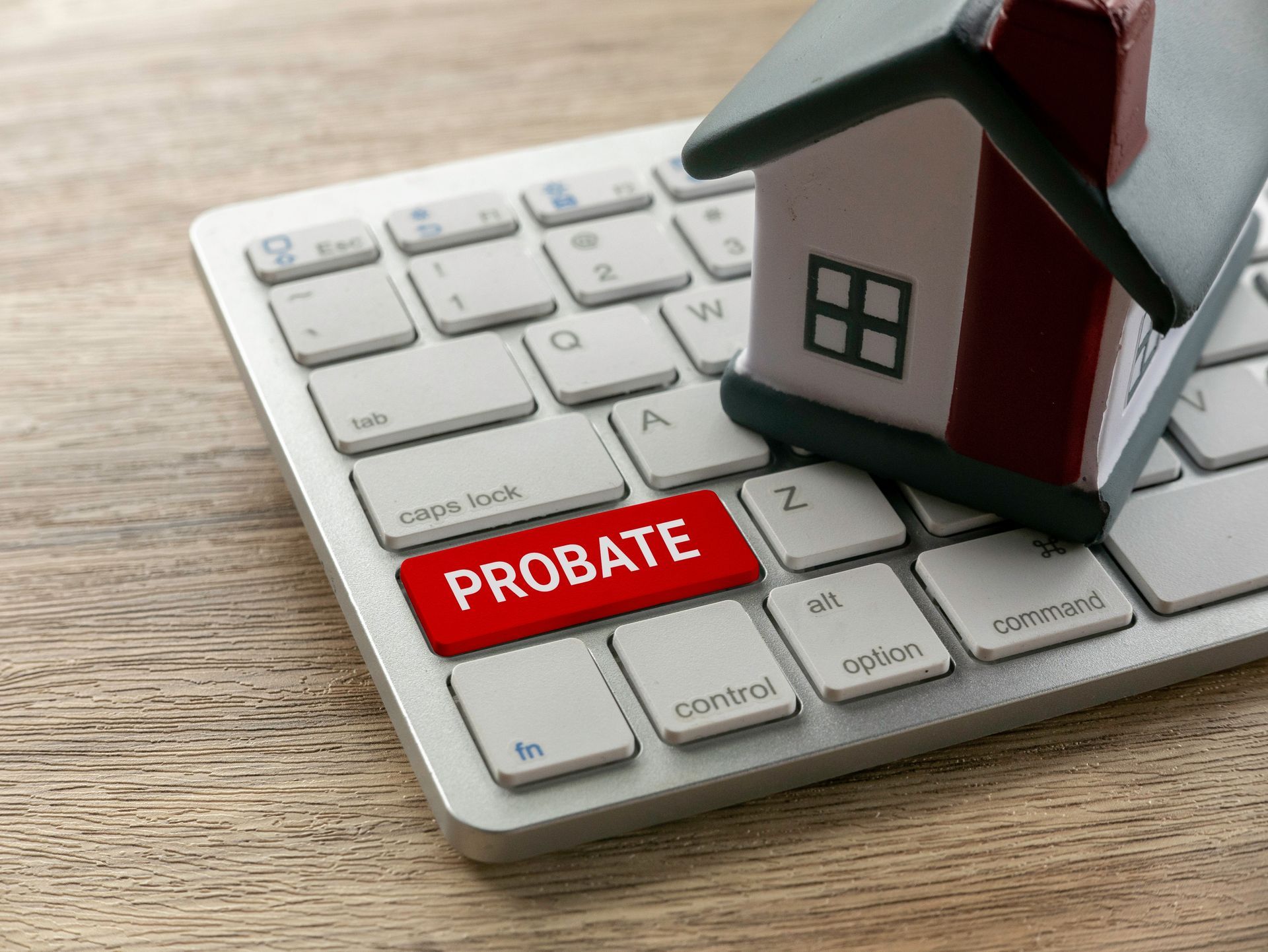 Red “PROBATE” label on a keyboard beside a small house model.