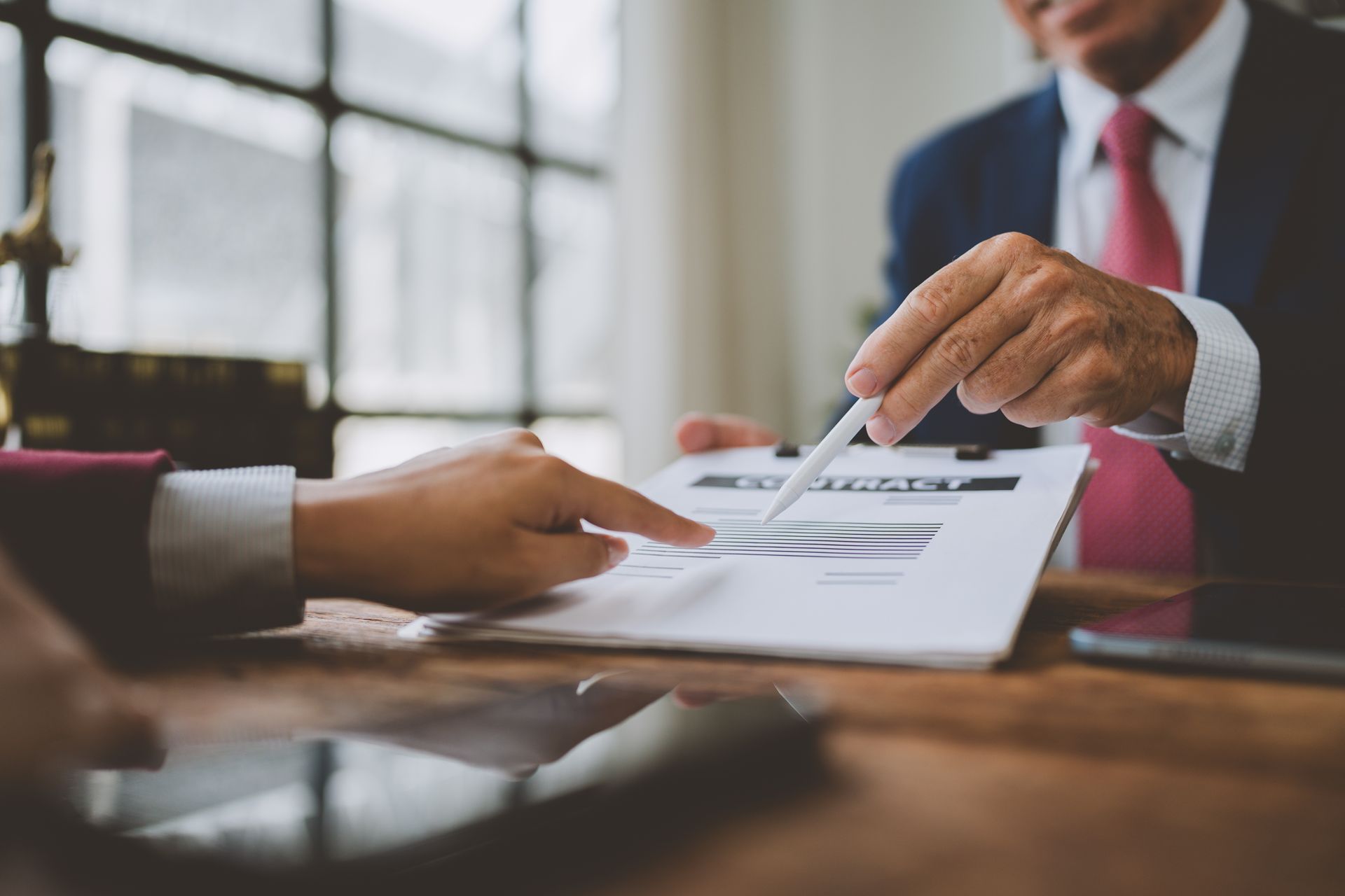 Hands signing a document across a conference table in a bright office