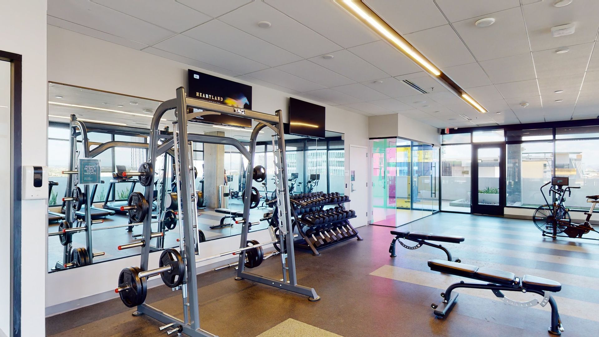 A gym with a lot of equipment and a lot of mirrors.