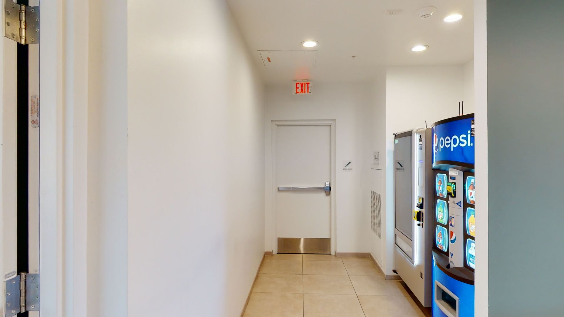 A hallway with a pepsi vending machine in the middle