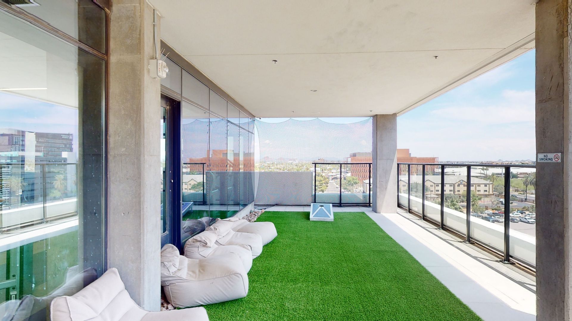 A balcony with a lush green lawn and white chairs.