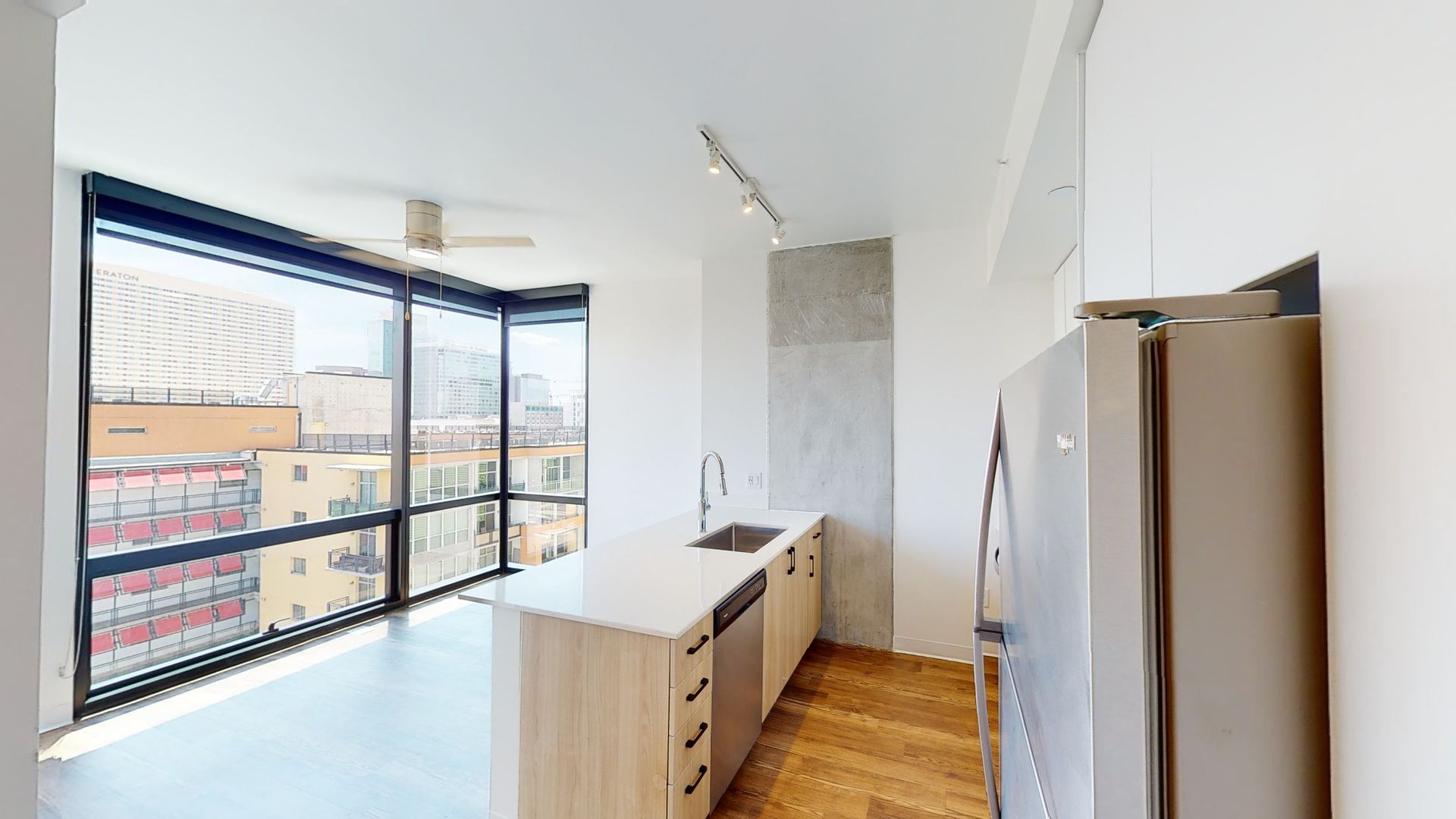 A kitchen with a refrigerator , sink , and large windows.