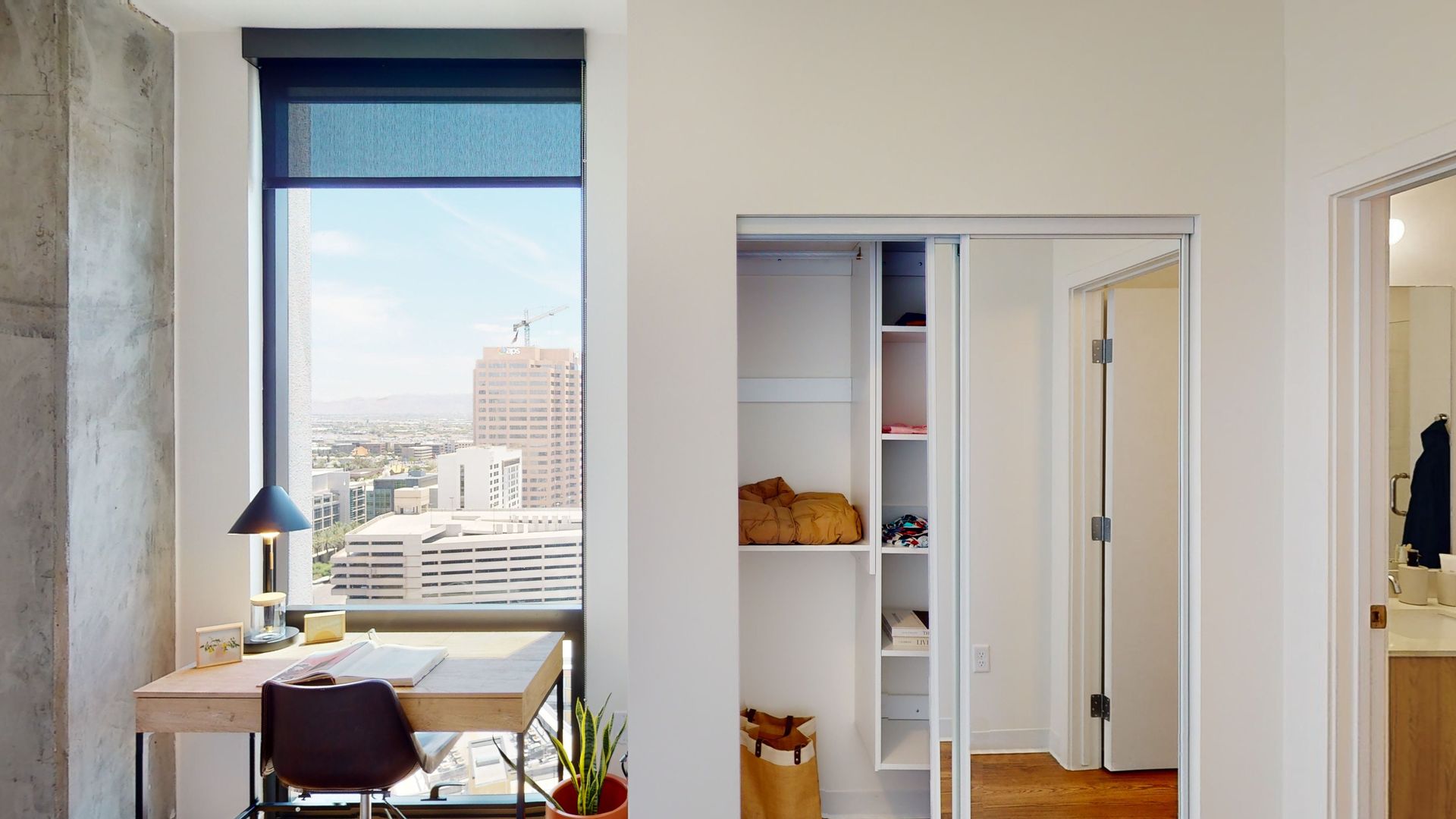 A bedroom with a desk , chair , window and closet.