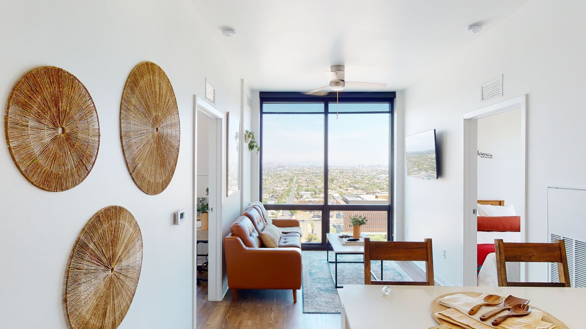 A living room with a couch , table , chairs and a large window.