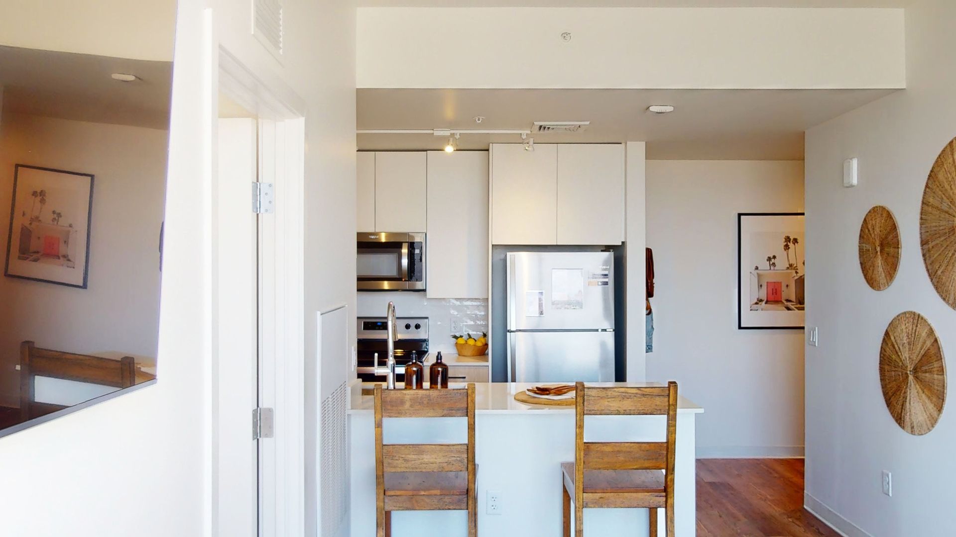 A kitchen with a refrigerator , microwave , sink and chairs