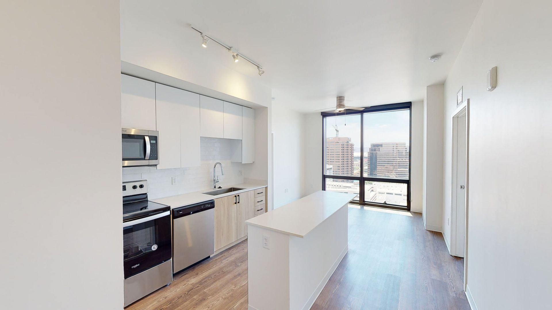 A kitchen with stainless steel appliances and a large window.