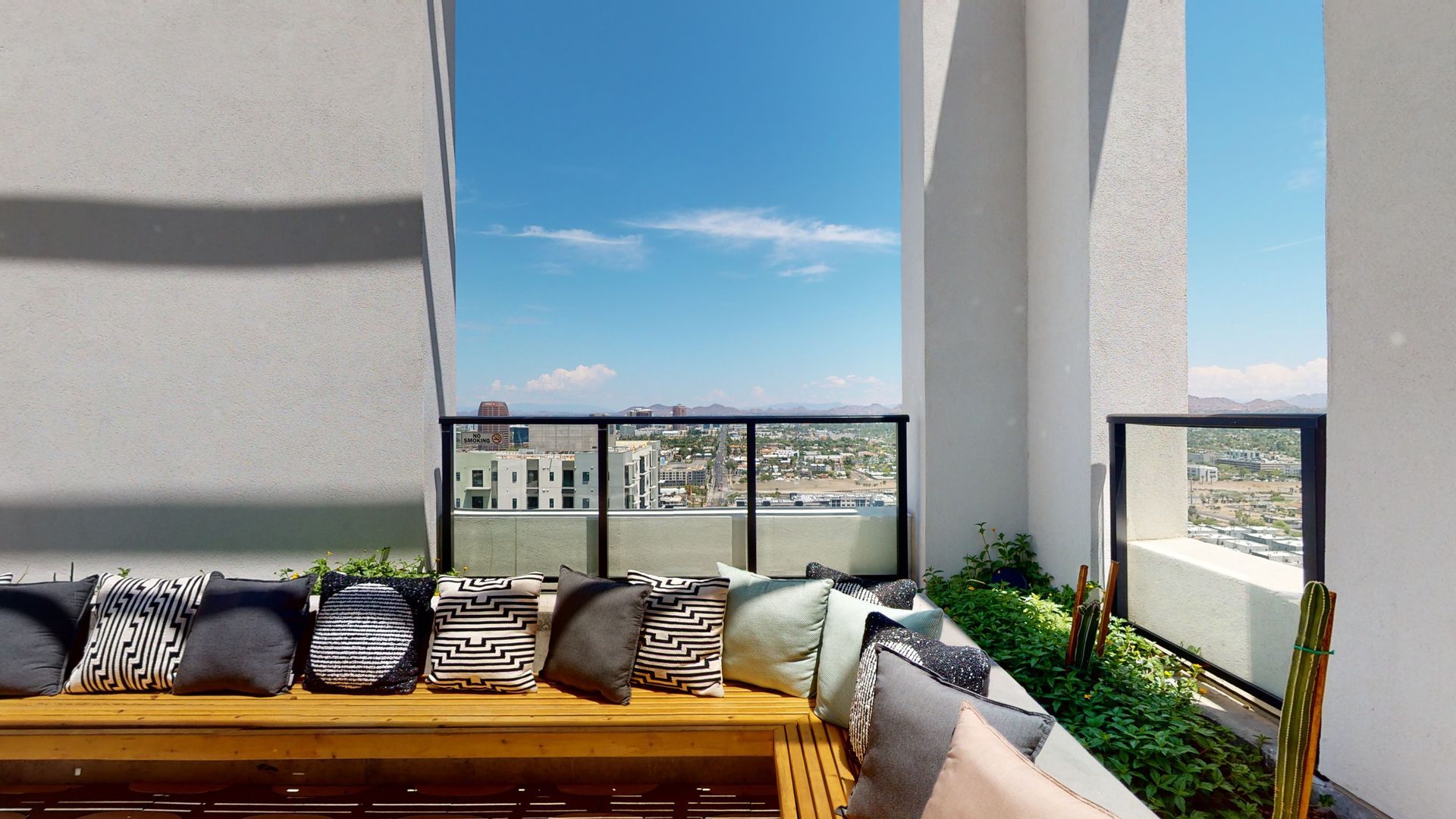 A balcony with a couch and pillows and a view of the city.