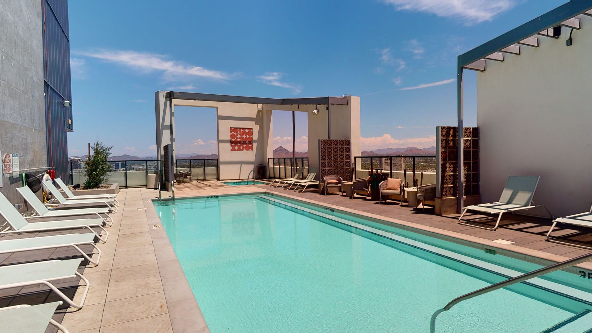 A large swimming pool surrounded by lounge chairs and a building.
