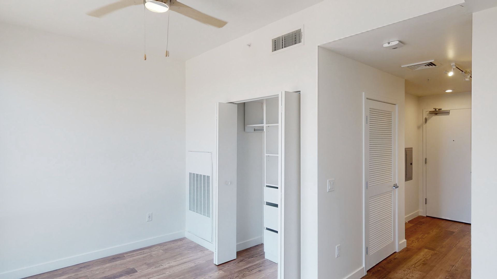 An empty room with a ceiling fan and a closet.