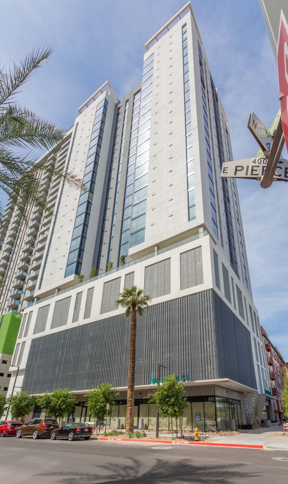 A tall building with a lot of windows is sitting on the corner of a city street.