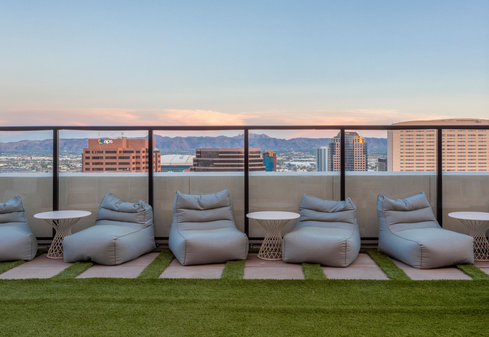A rooftop patio with tables and chairs and a grill.