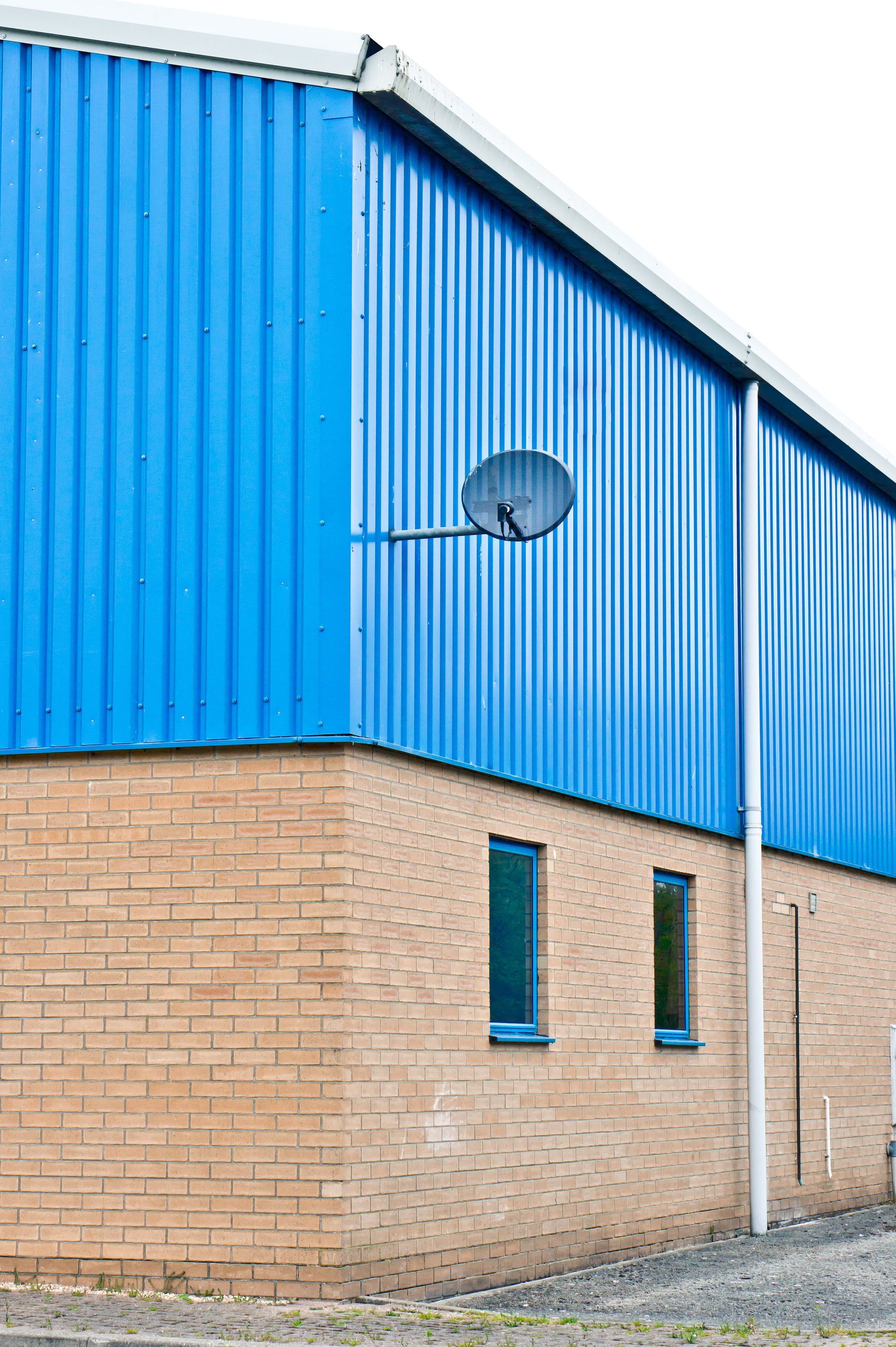 A blue building with a satellite dish on the side of it.