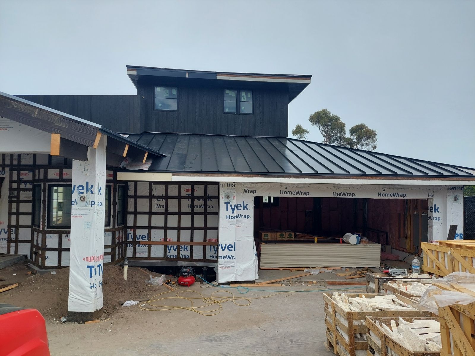 A house is being built with a black metal roof.